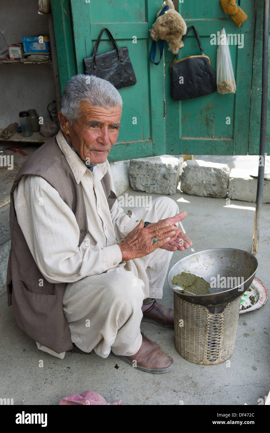 Shopkeeper rolling niswar (a type of chewing tobacco) on the verandah of his shop, Karimabad, Hunza Valley, Gilgit-Baltistan, Pakistan Stock Photo