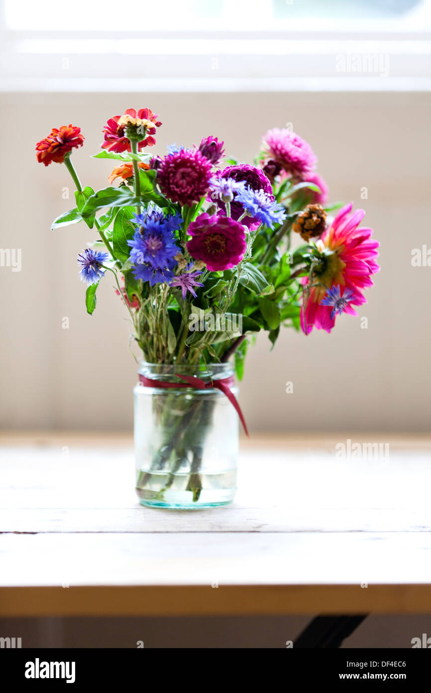 A small bunch of freshly picked flowers arranged in a small glass jar Stock Photo