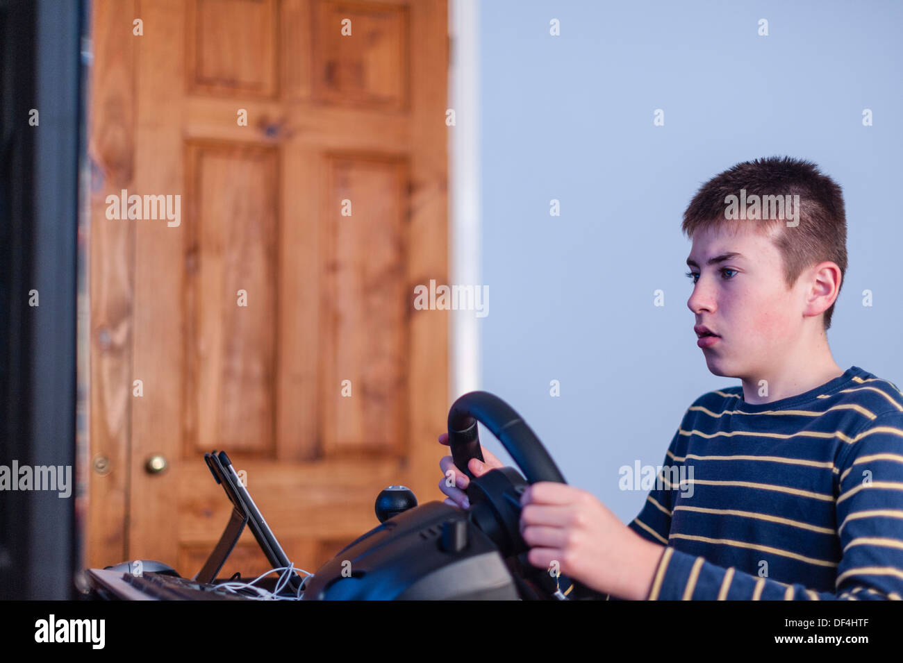 A 13 year old boy playing a computer driving game using a