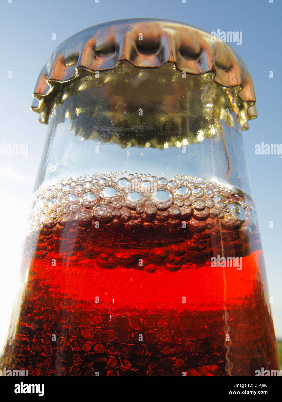 Bottle neck with crown cap and a red liquid and many bubbles Stock