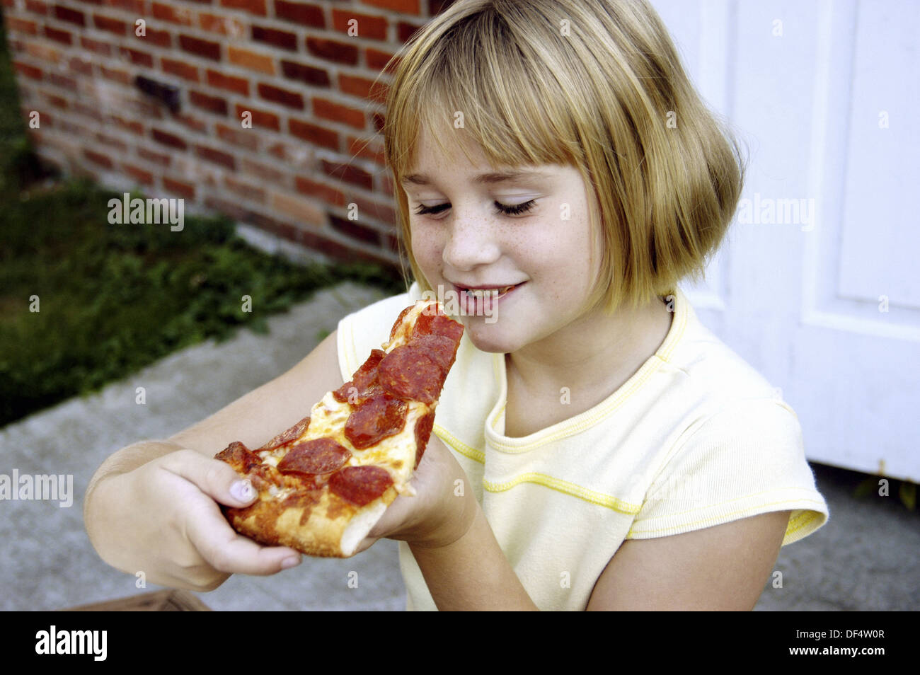 Seven year old girl eats pizza Stock Photo