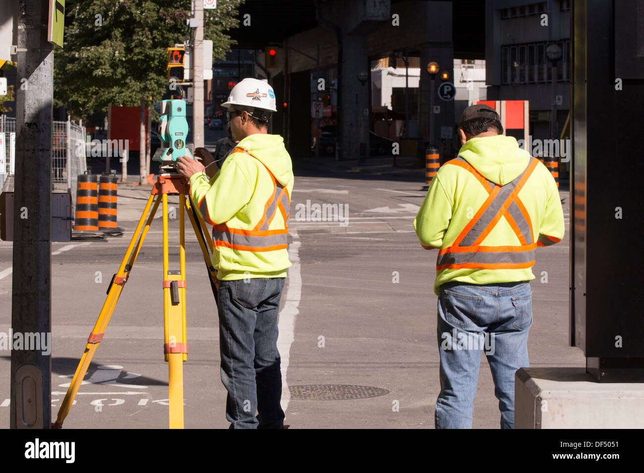 Surveyor adjusting theodolite at road construction site in downtown Toronto Stock Photo