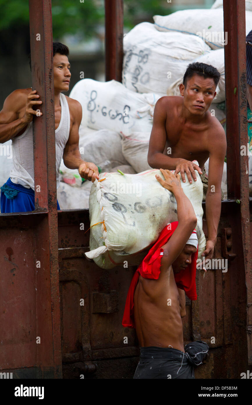 Men unload a truck near a railway station in Yangon, Burma. Stock Photo