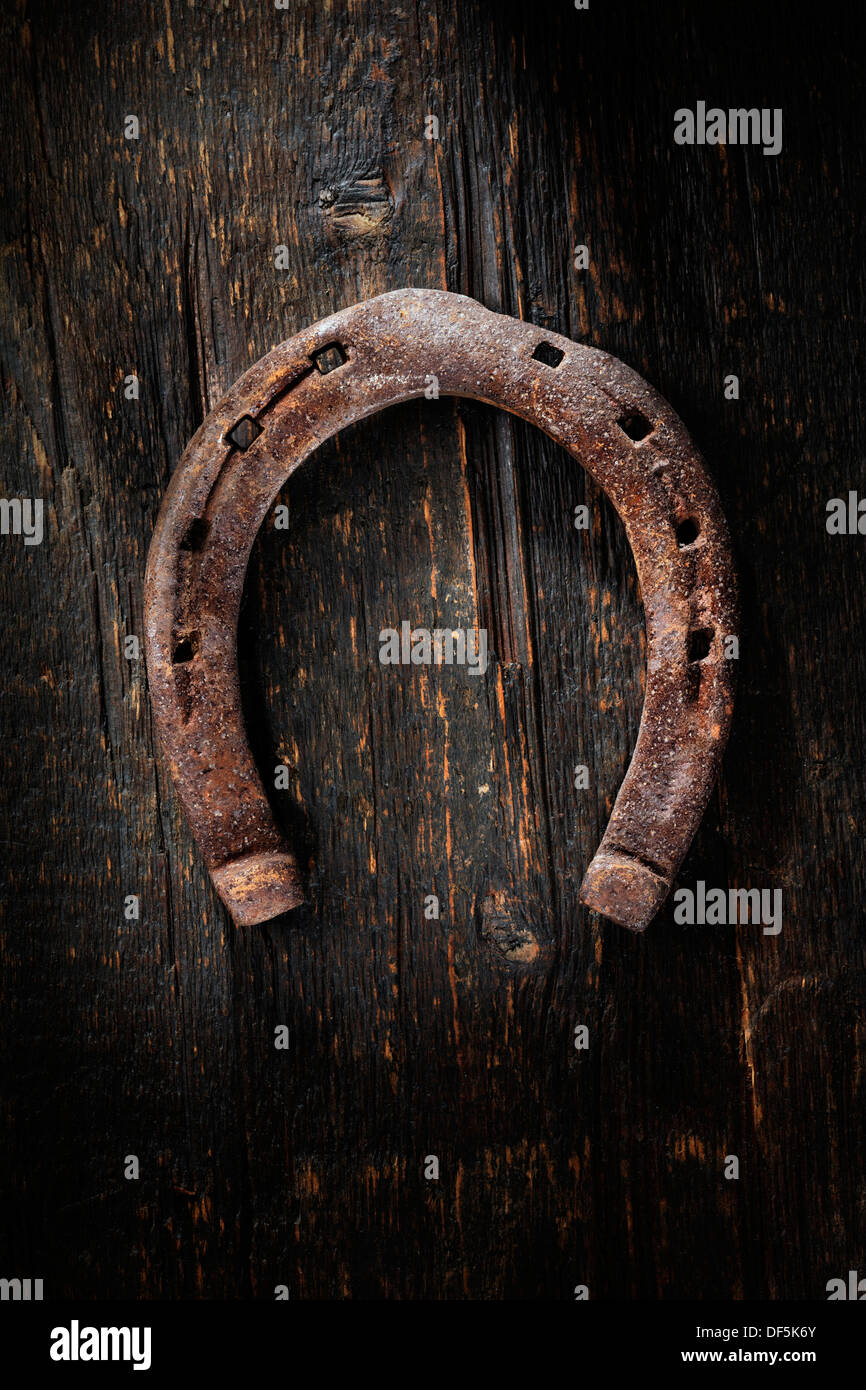Old worn and rusty horseshoe on wooden background. Stock Photo