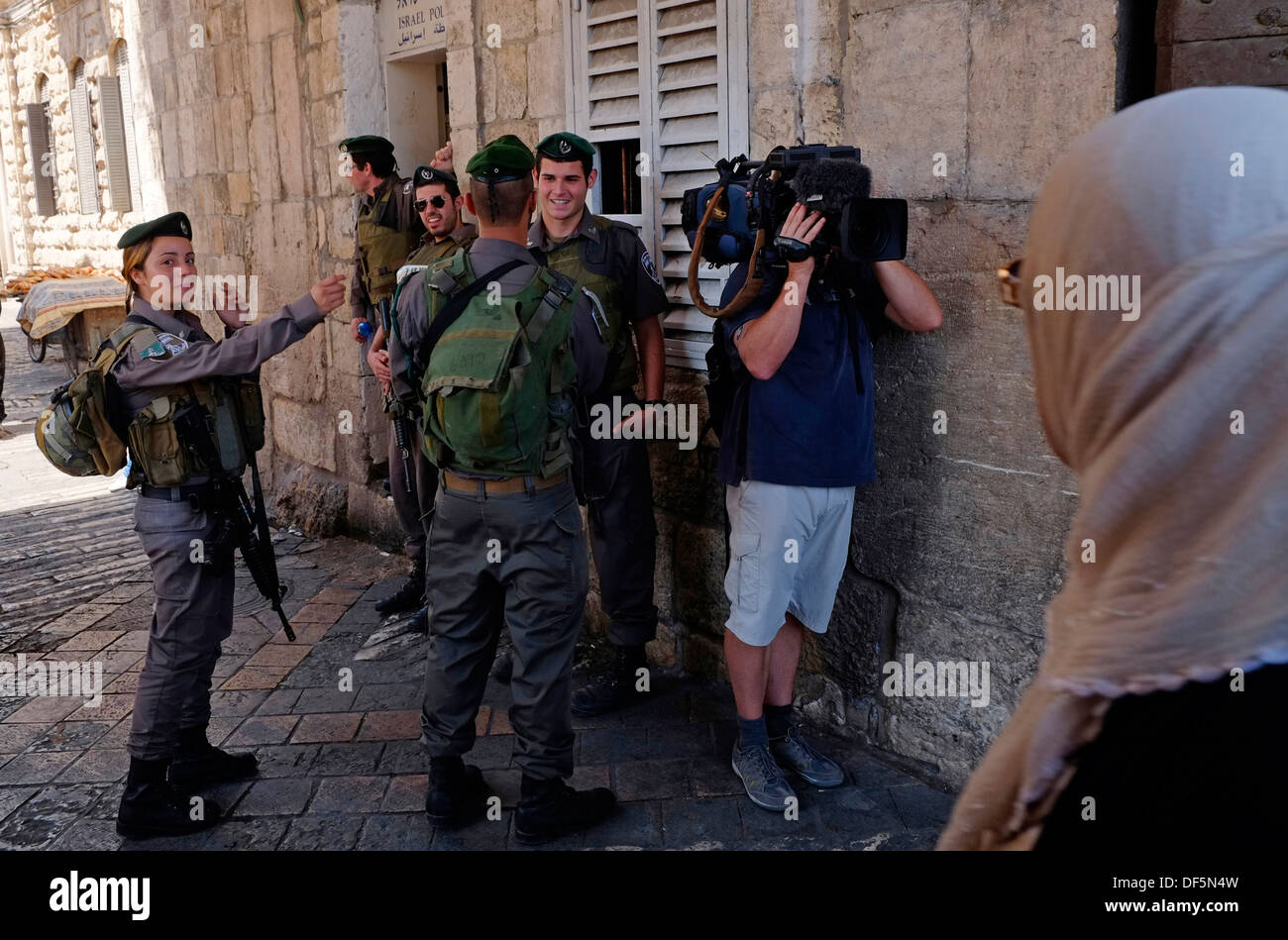 A TV cameraman filming in the old city of Jerusalem amid Israeli border police and Palestinian pedestrians Israel Stock Photo