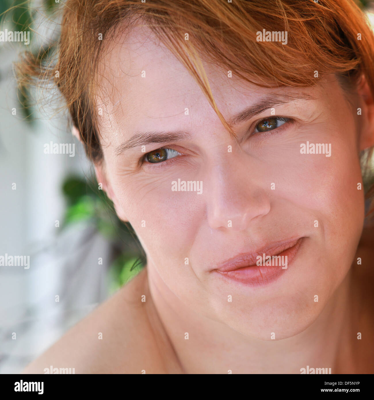 Outdoor closeup portrait of slightly smiling young Caucasian woman Stock Photo