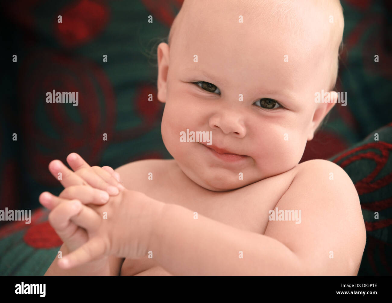 Closeup portrait of funny smiling Caucasian baby above dark background Stock Photo