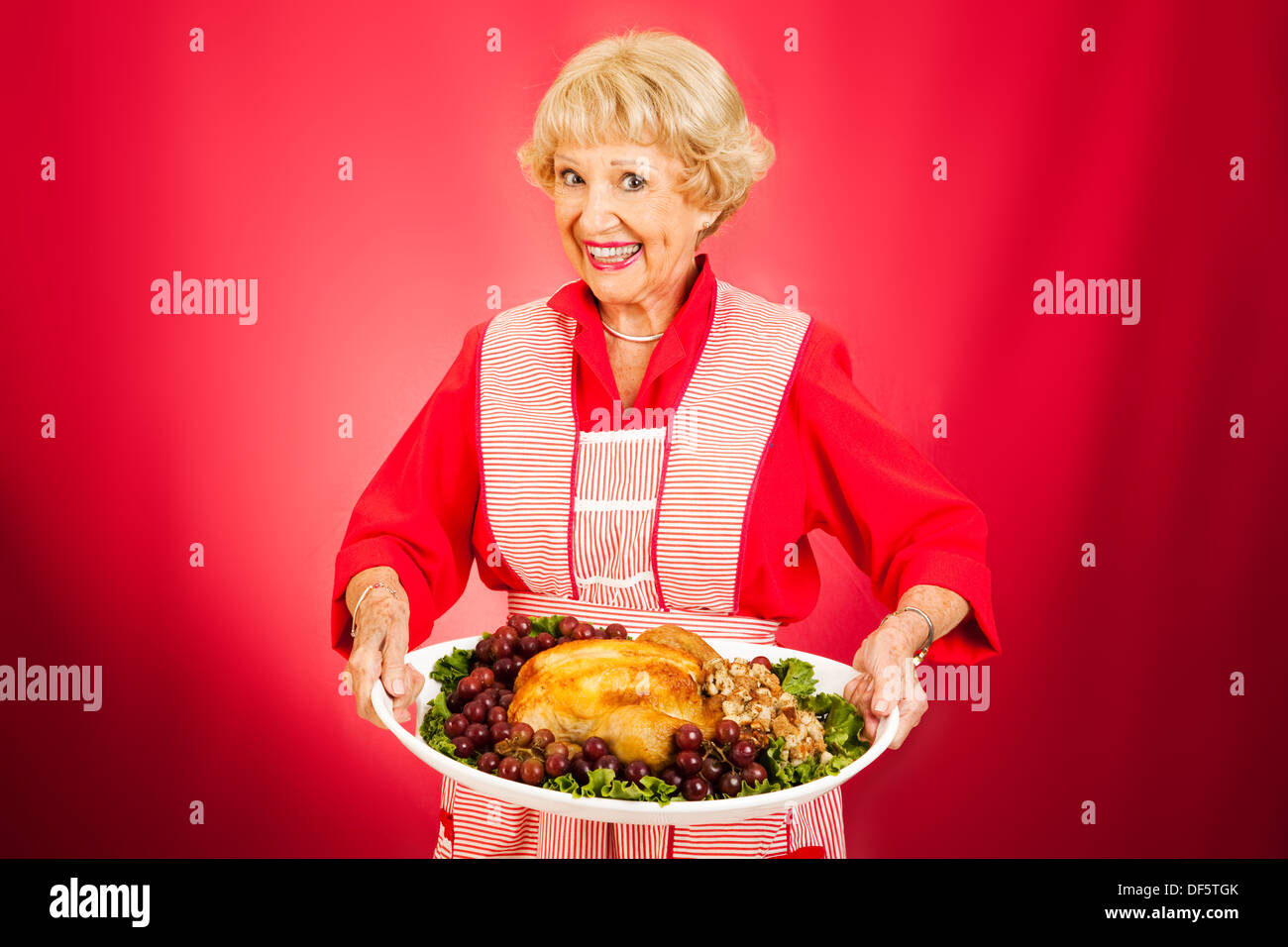 Sweet grandmother holding a beautifully cooked turkey dinner. Stock Photo