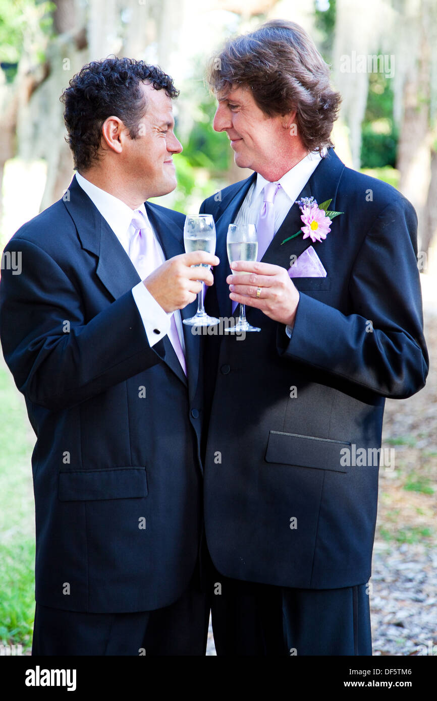 Gay couple toasting each other with champagne at their wedding.  Stock Photo