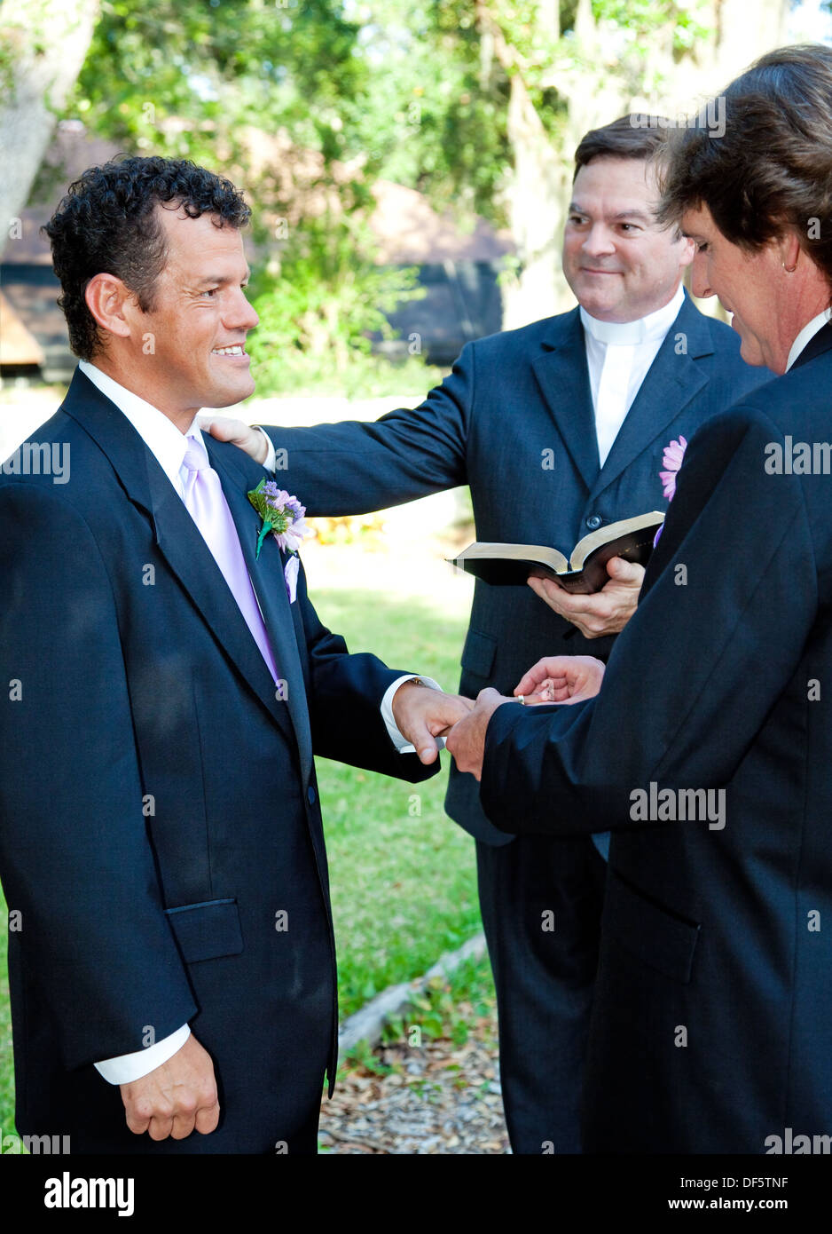 Groom slips a ring on his husband's finger during a gay marriage ceremony.  Stock Photo