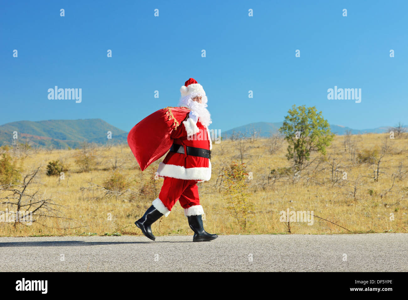 Male santa claus with bag walking on an open road Stock Photo