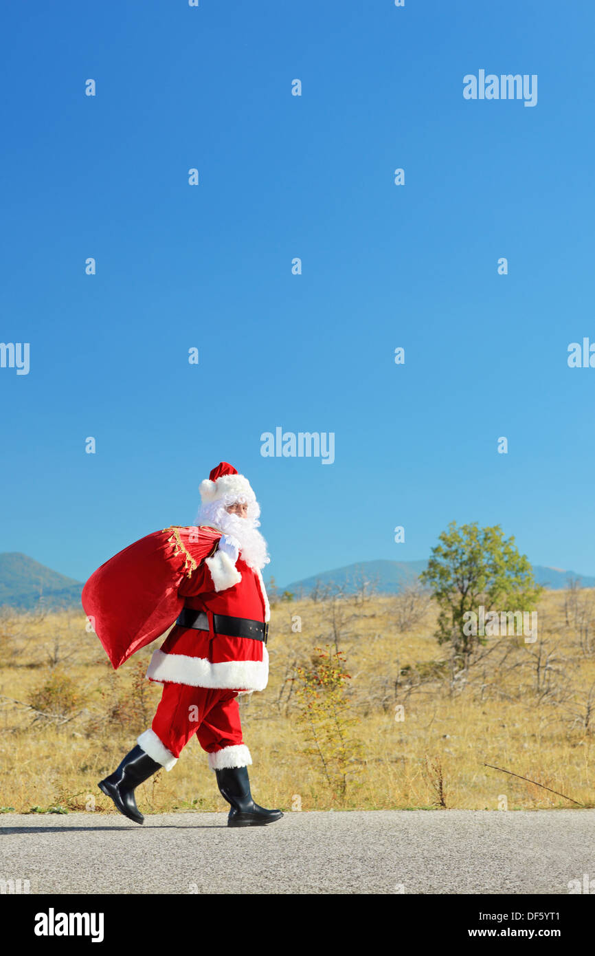 Santa claus with bag walking on an open road Stock Photo