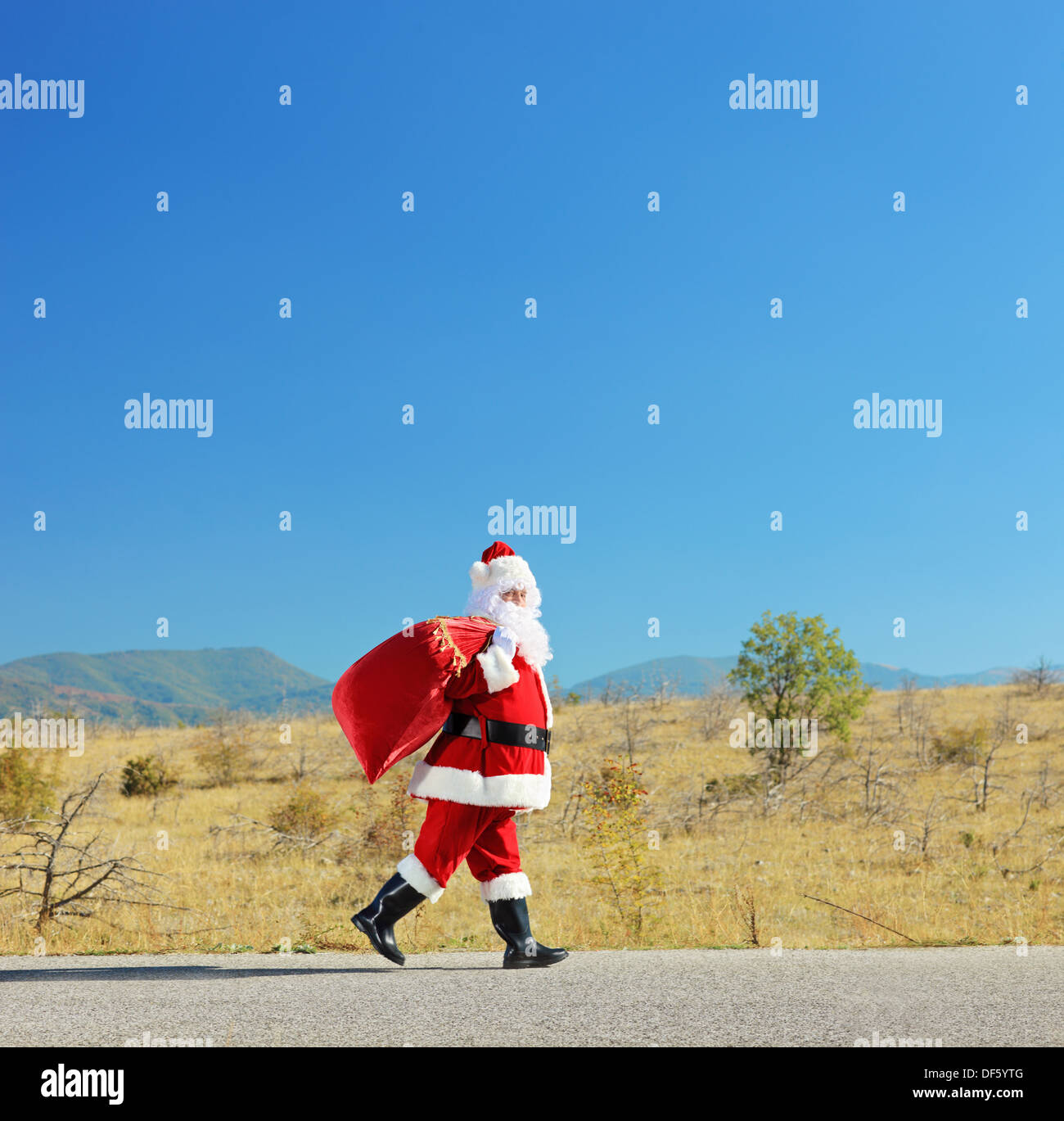 Full length portrait of a santa claus with bag walking on an open road Stock Photo