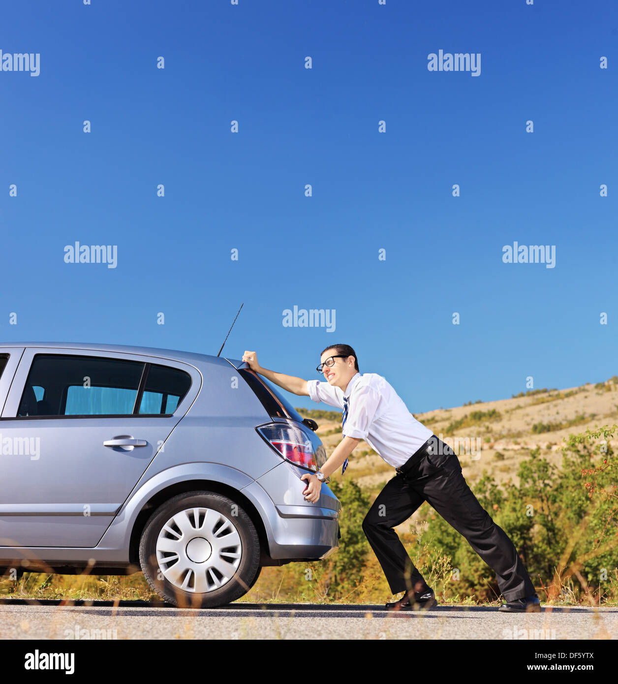 Young businessman pushing his car with empty fuel tank Stock Photo