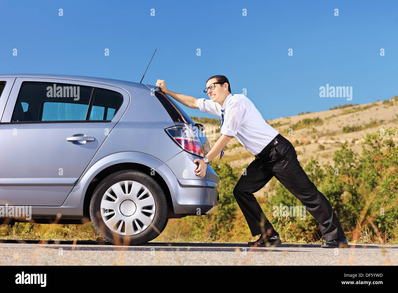 Young man pushing his broken car or a car out of gas Stock Photo
