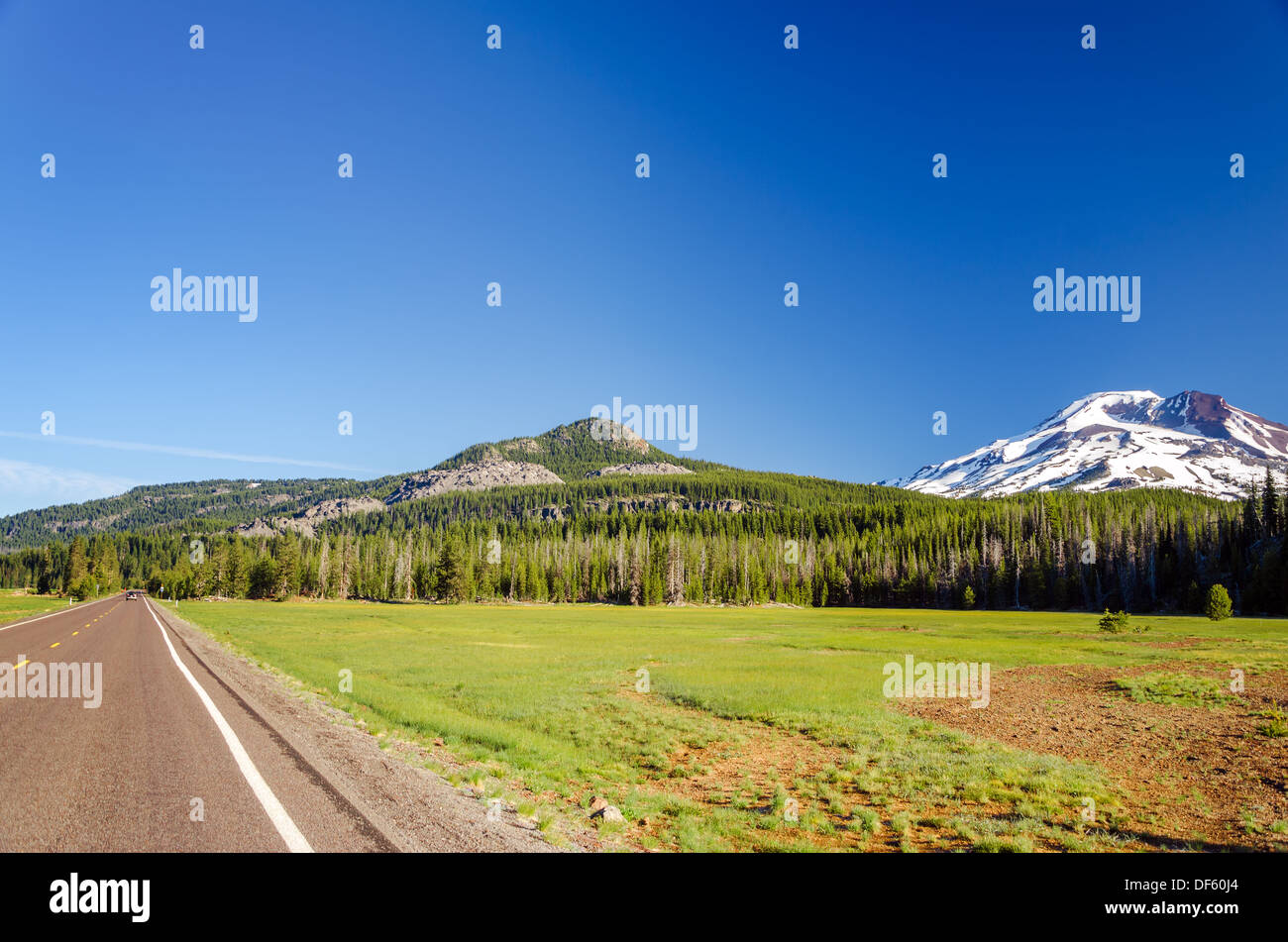 Highway passing next to a forest and South Sister mountain near Bend, Oregon Stock Photo