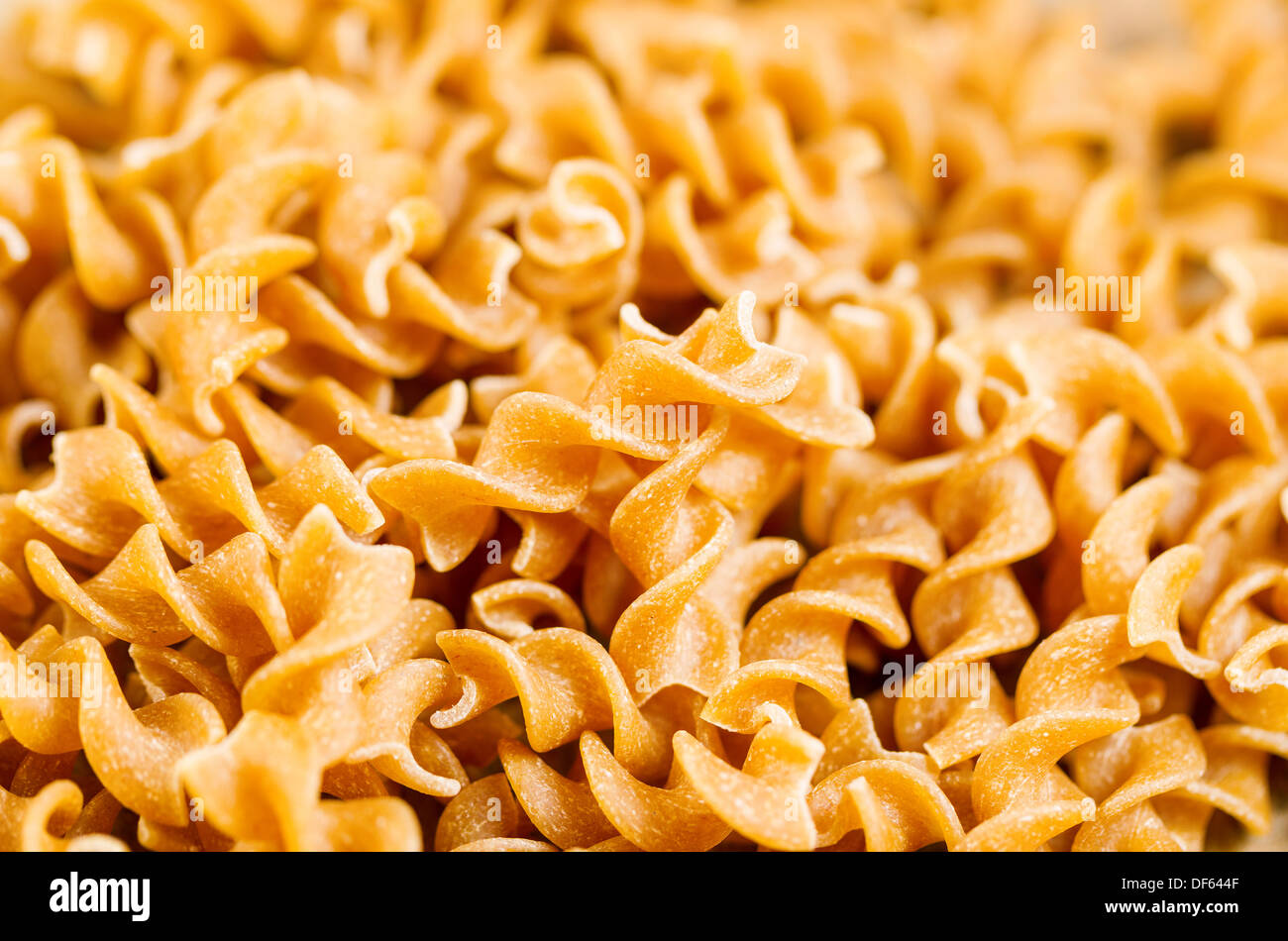 Closeup horizontal photo of uncooked curly pasta noodles in a pile