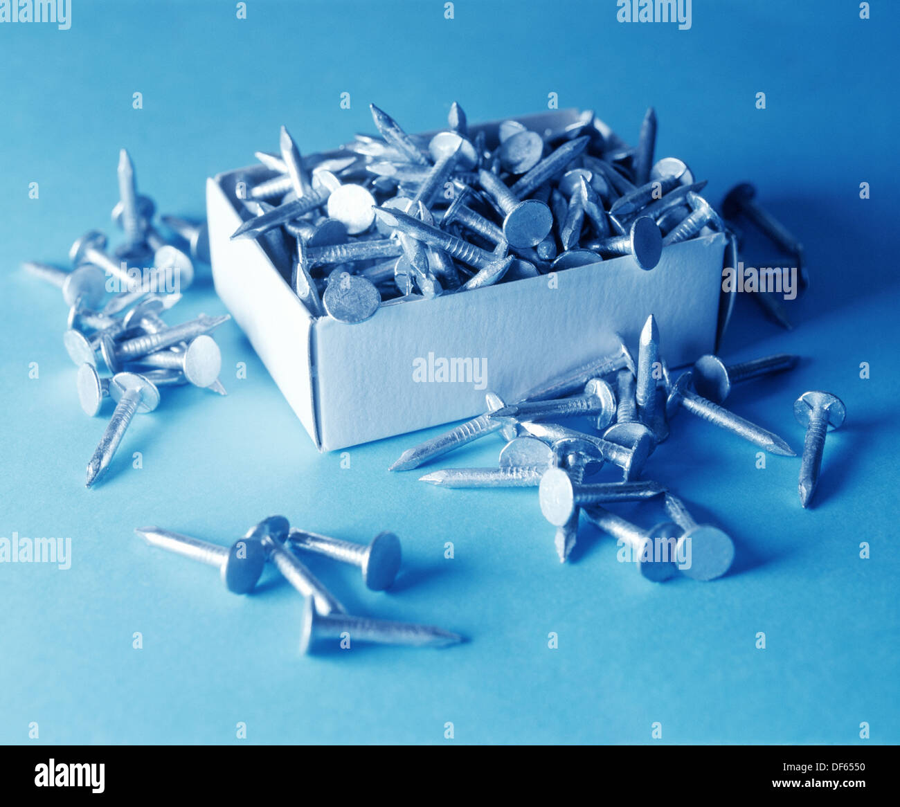 Short nails in a small cardboard box and spilled over the edge on the