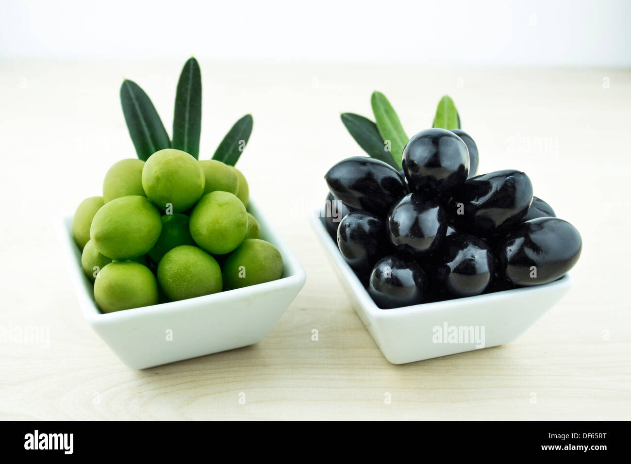 Black and Green Olives with leaves on a white background Stock Photo
