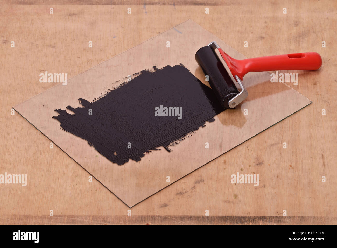 Black printing ink on a sheet of glass with a rubber roller Stock Photo