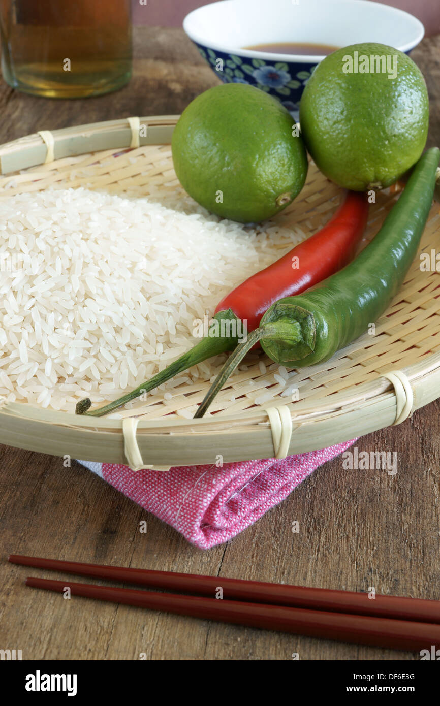 Limes, chilli's, rice and soy sauce, Asian food ingredients. Focus on Chilis and rice in foreground Stock Photo