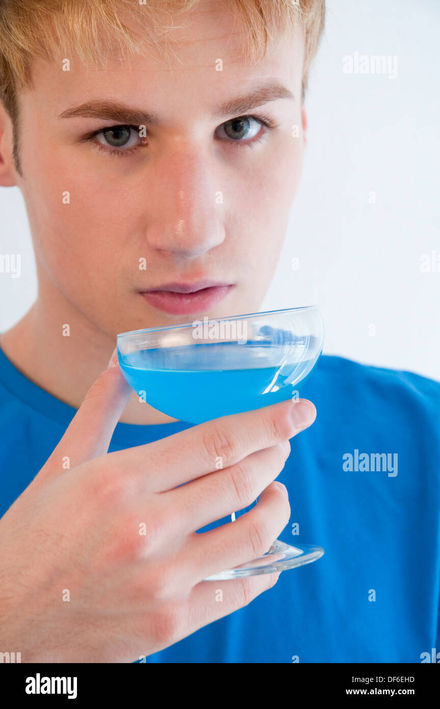 Young man drinking a blue isotonic drink, matching with his T-shirt. Close view. Stock Photo