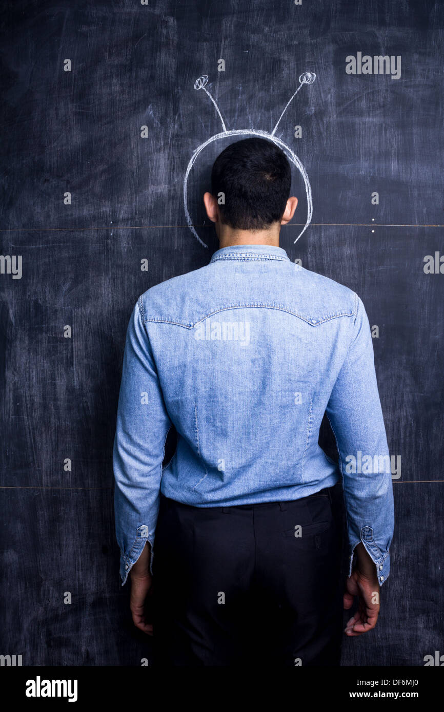 Rear view of young man by blackboard imagining himself as an astronaut Stock Photo