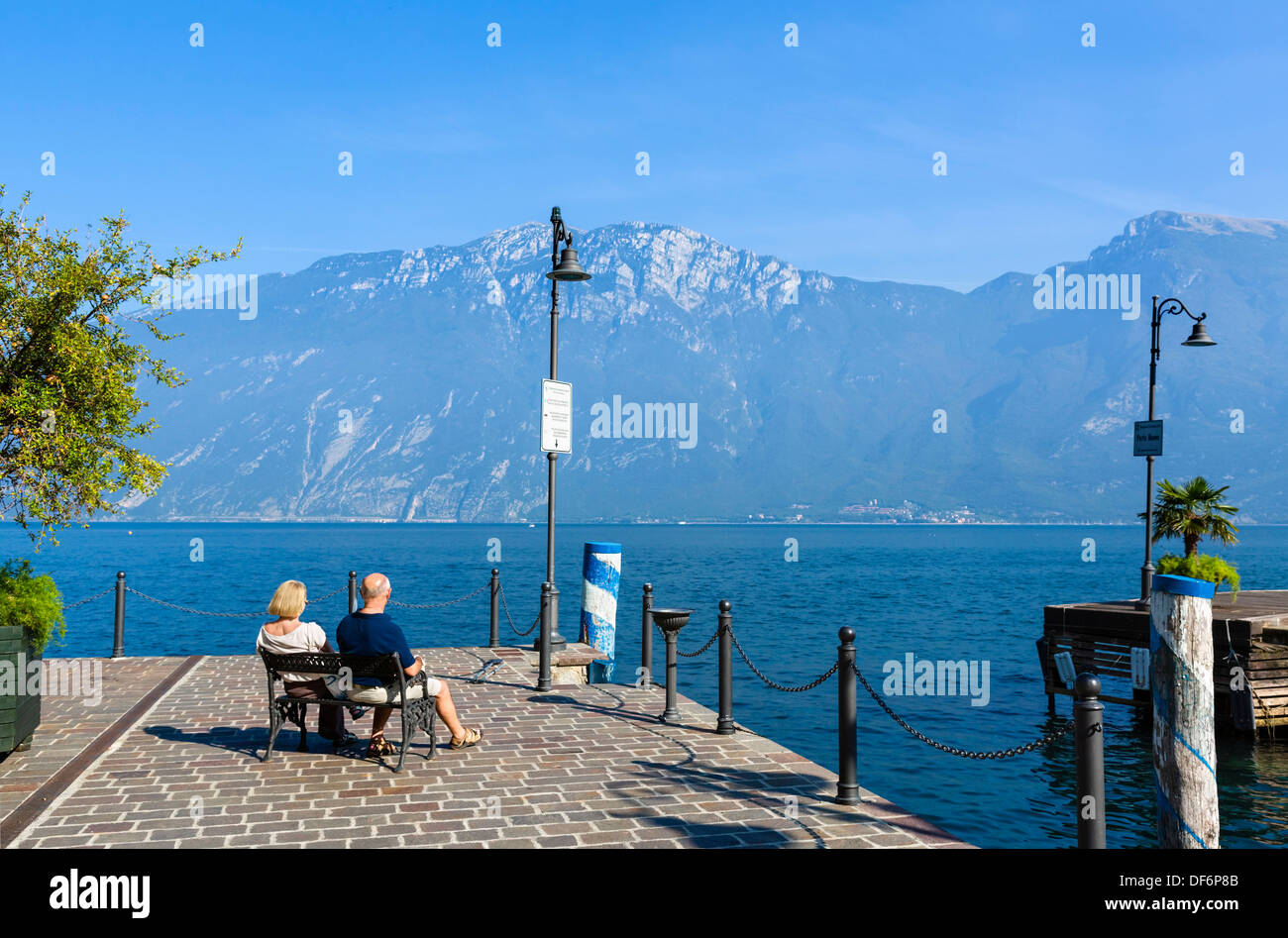 Middle aged couple sitting on the lakefront in Limone sul Garda, Lake Garda, Italian Lakes, Lombardy, Italy Stock Photo