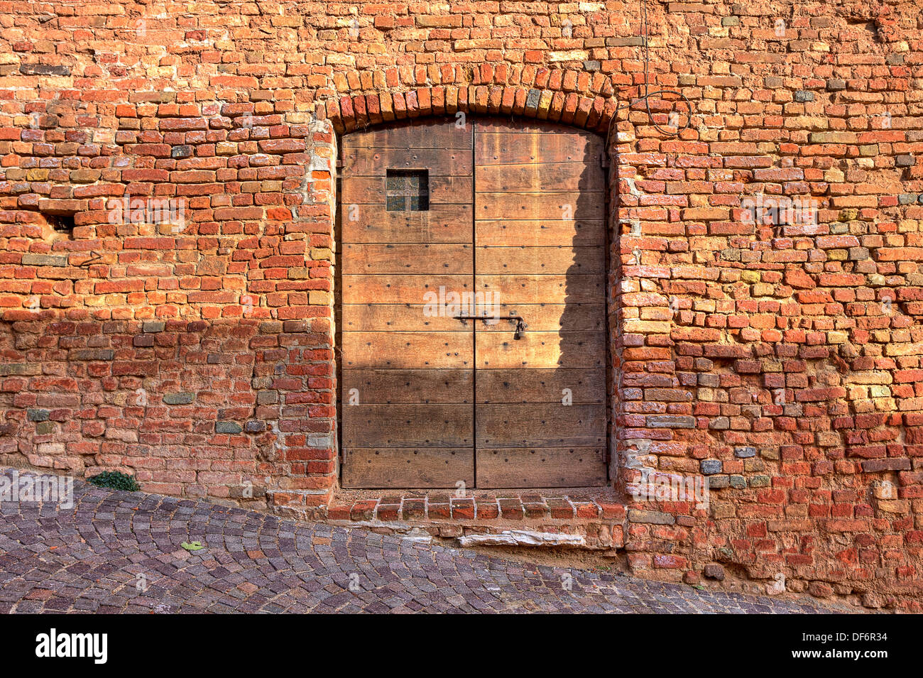 Red brick exterior wall of old house with wooden door on cobbled street