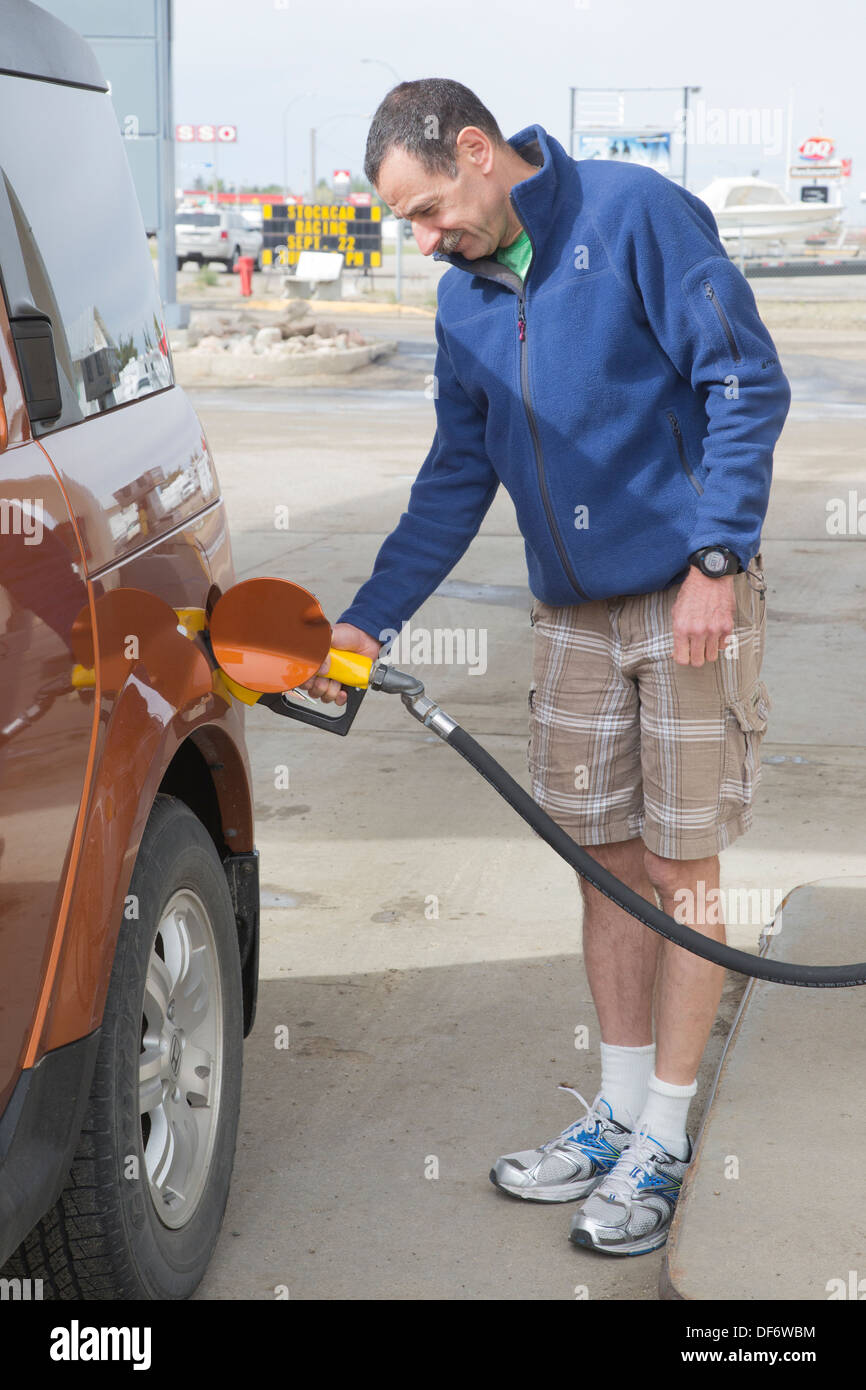 Man on road trip pumping gas into his truck at service station Stock Photo