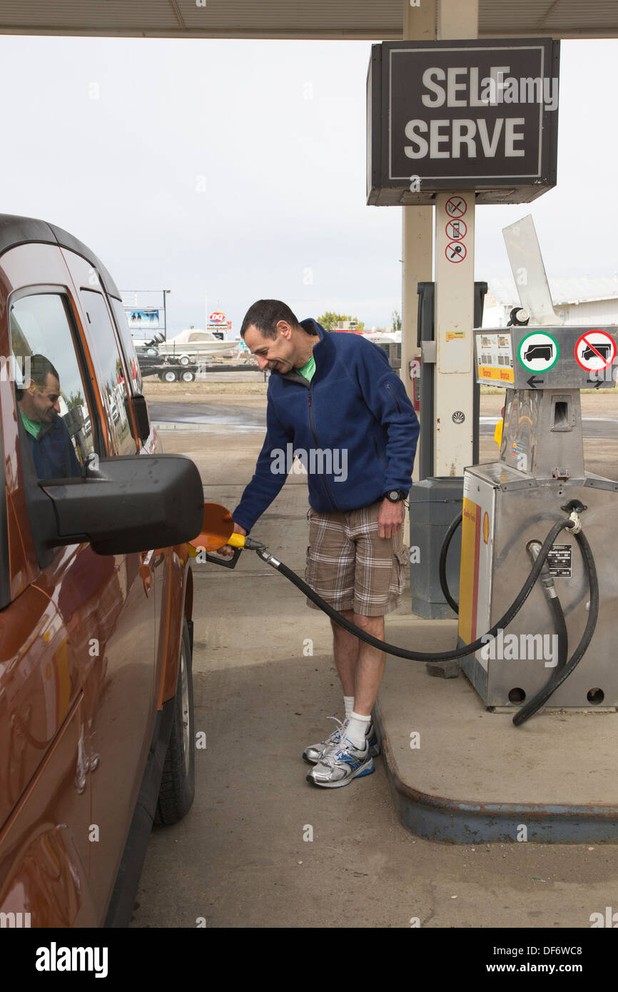 Man on road trip pumping gas into his truck at self service station in Alberta, Canada Stock Photo