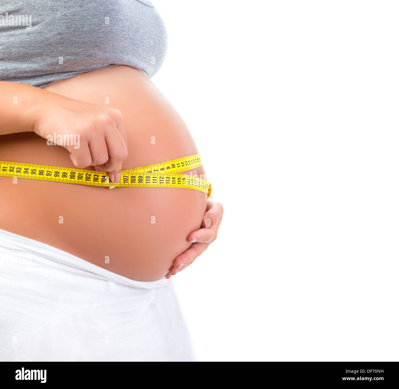 Expectant female measuring tummy by yellow centimeter isolated on white background, baby care, happy motherhood, new life Stock Photo