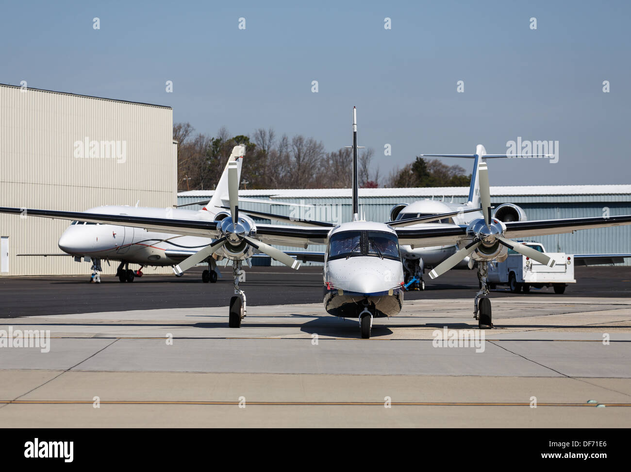 A large private turbo-prop airplane by hangers and private jets Stock Photo