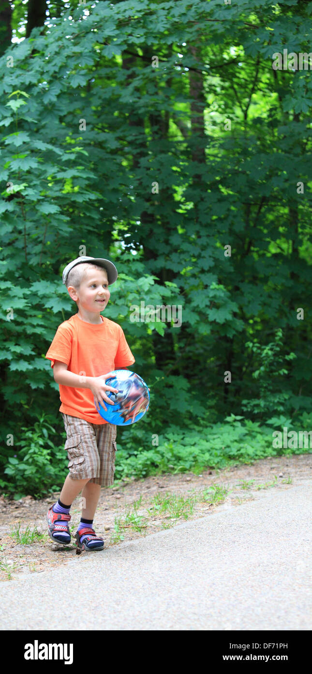 Boy in action young kid playing with ball in park outdoors. Healthy ...