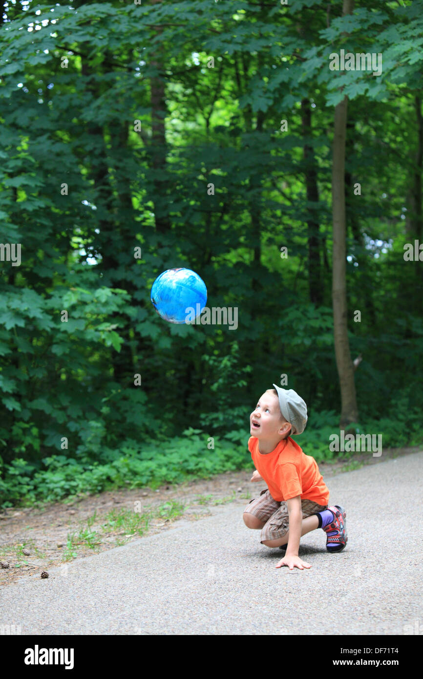 Boy in action young kid playing with ball in park outdoors. Healthy ...