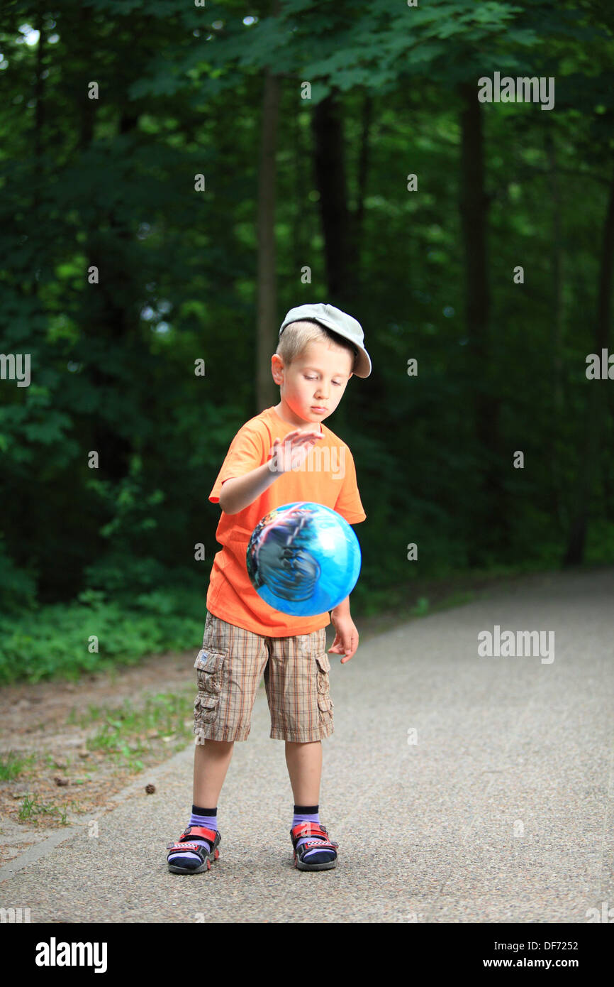 Boy in action young kid playing with ball in park outdoors. Healthy ...