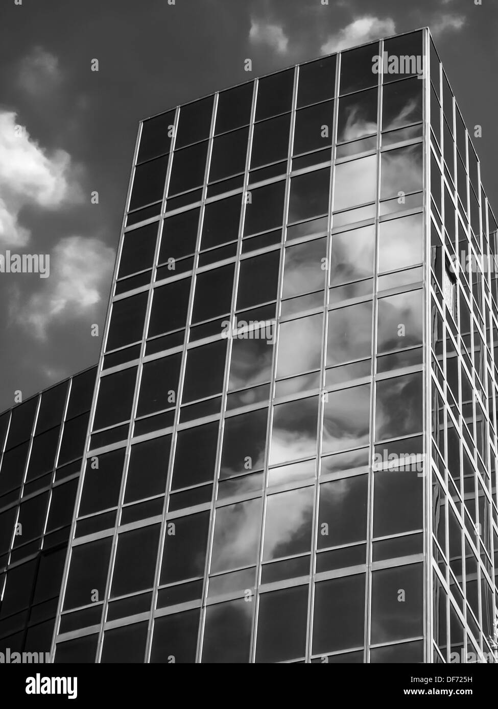 A Black and White image of a glass office tower block with clouds