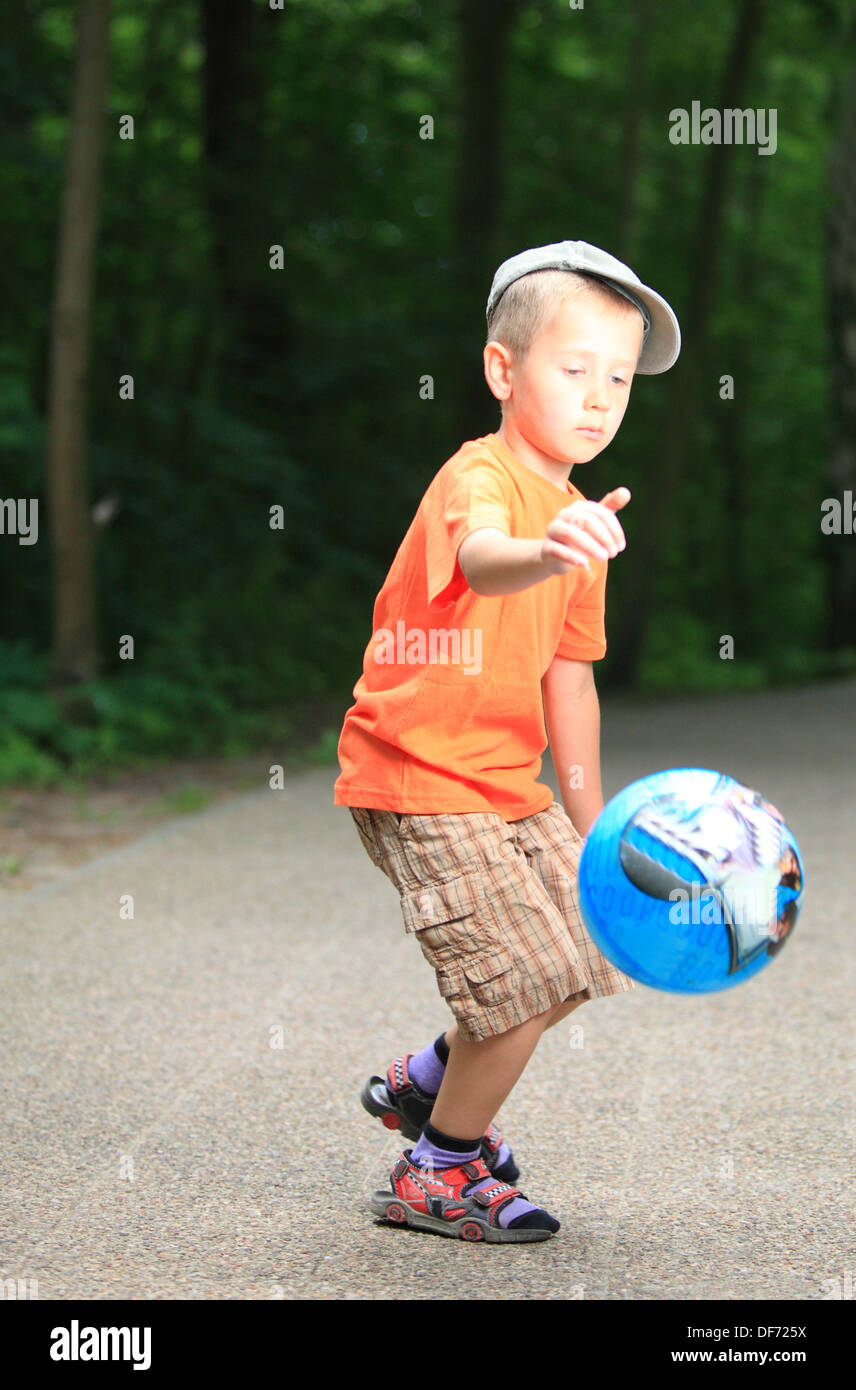 Boy in action young kid playing with ball in park outdoors. Healthy ...