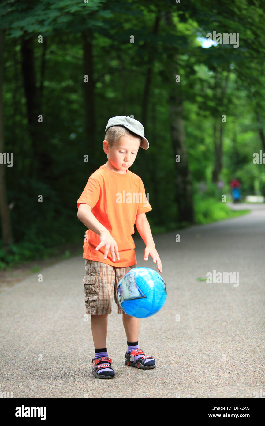 Boy in action young kid playing with ball in park outdoors. Healthy ...