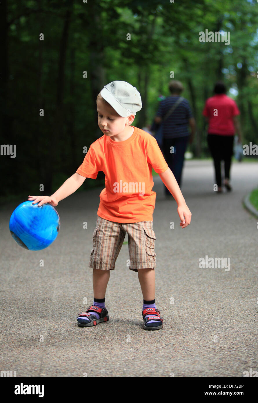 Boy in action young kid playing with ball in park outdoors. Healthy ...