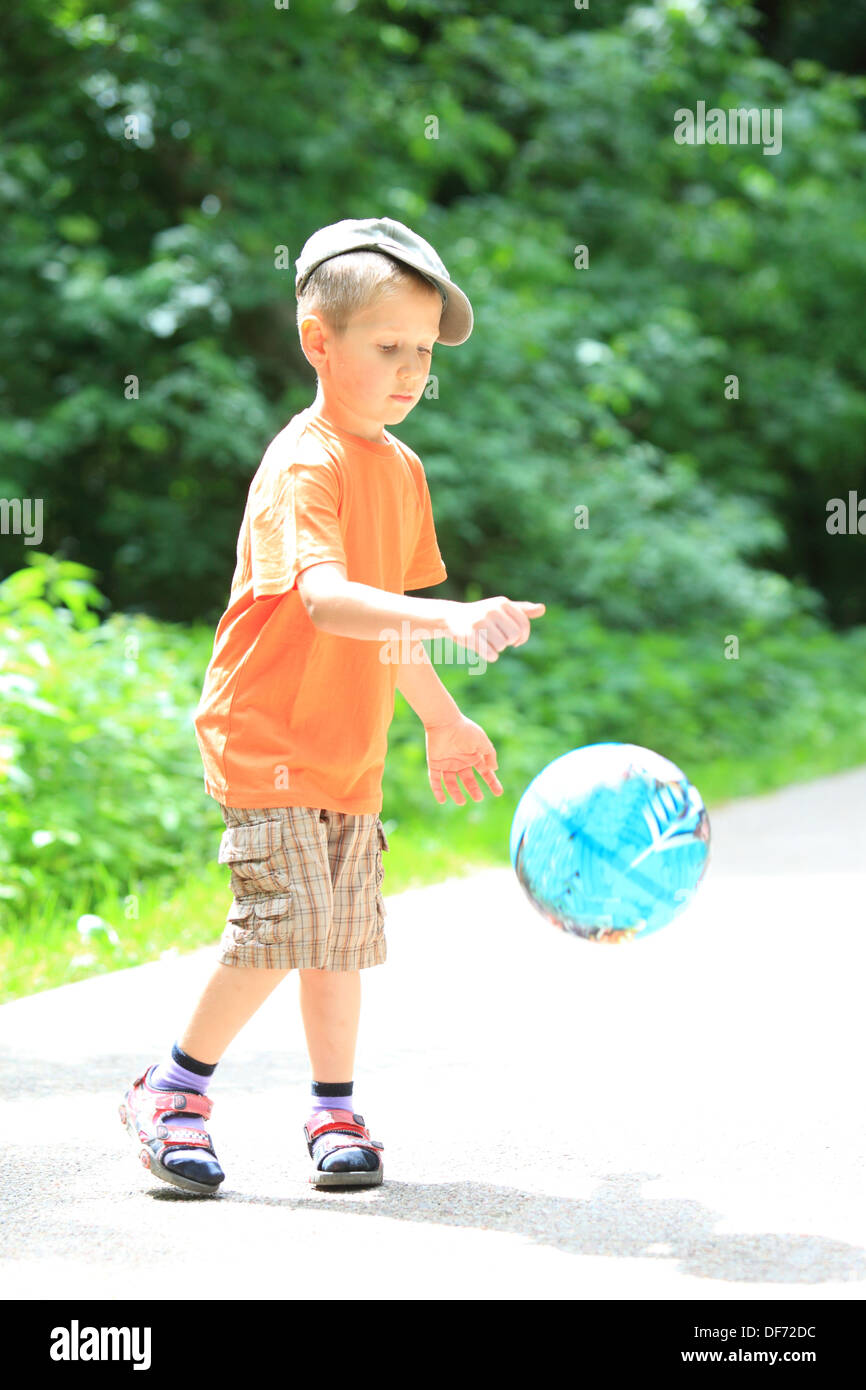 Boy in action young kid playing with ball in park outdoors. Healthy ...