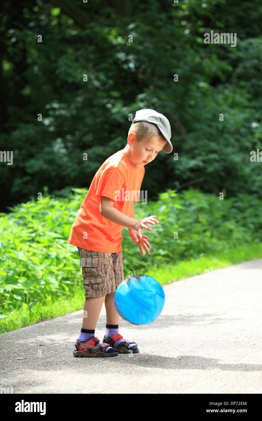 Boy in action young kid playing with ball in park outdoors. Healthy ...