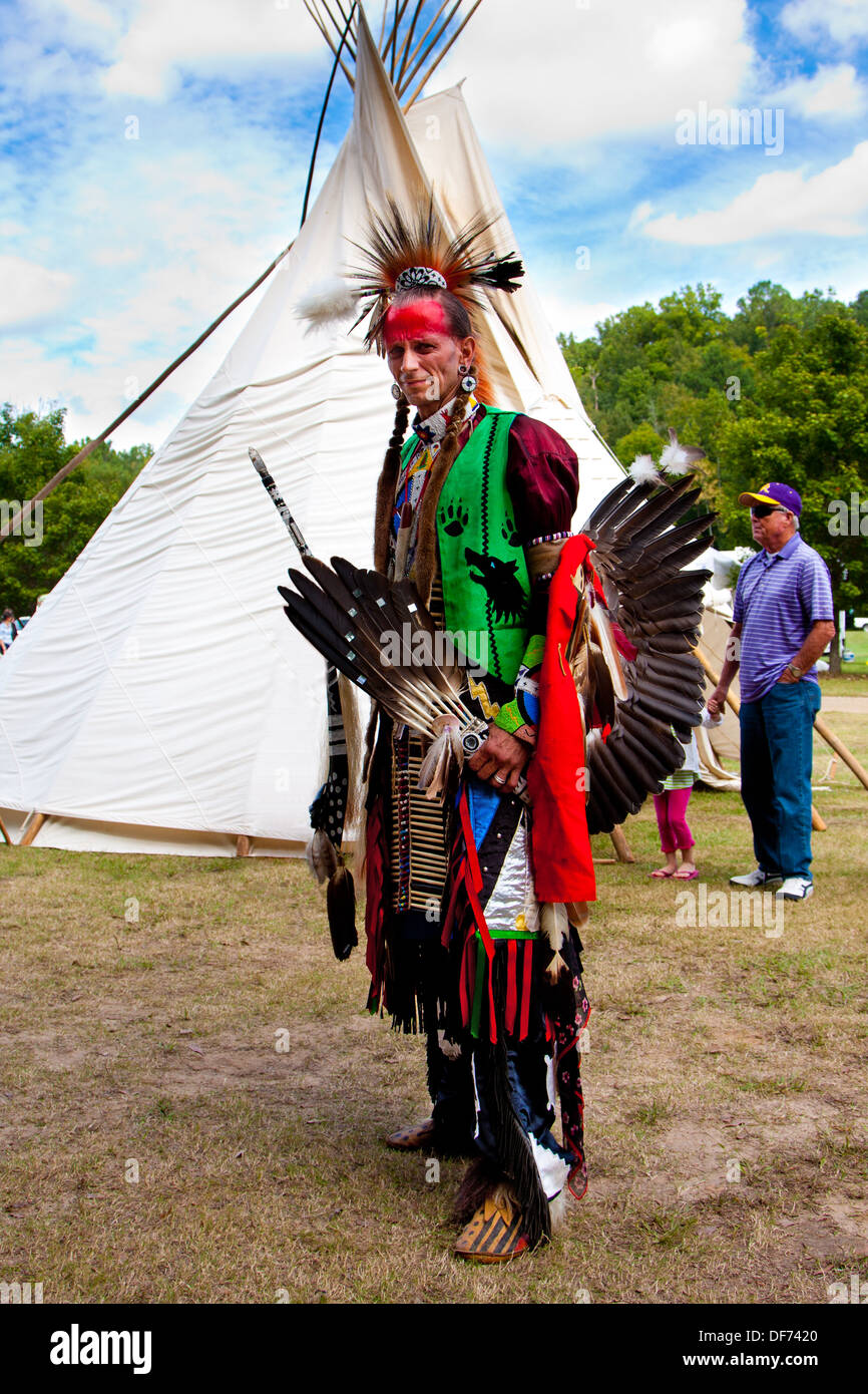 Native American Indian warrior with weapons standing in front of Tipi Tepee Stock Photo