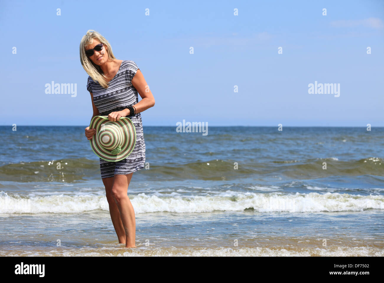 Full length mature woman with hat on beach enjoying summer holiday ...