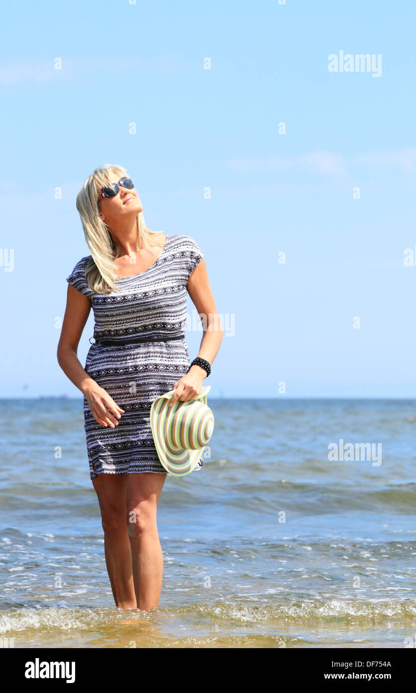 Full length mature woman with hat on beach enjoying summer holiday ...
