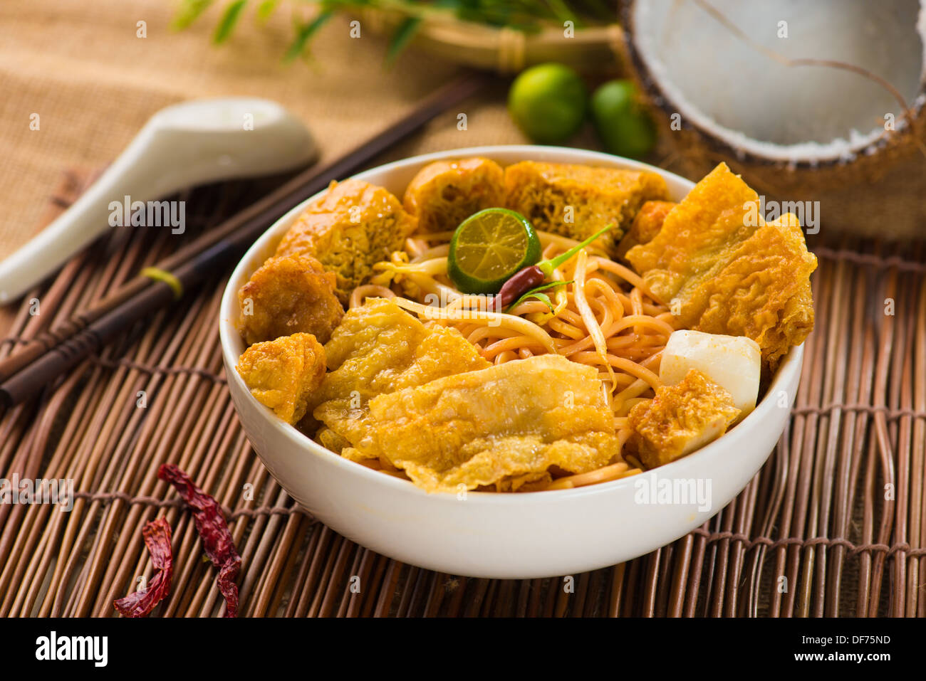chopstick and laksa curry noodles with plenty of raw ingredients as background Stock Photo
