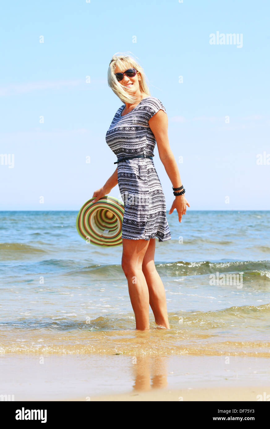 Full length mature woman with hat on beach enjoying summer holiday ...