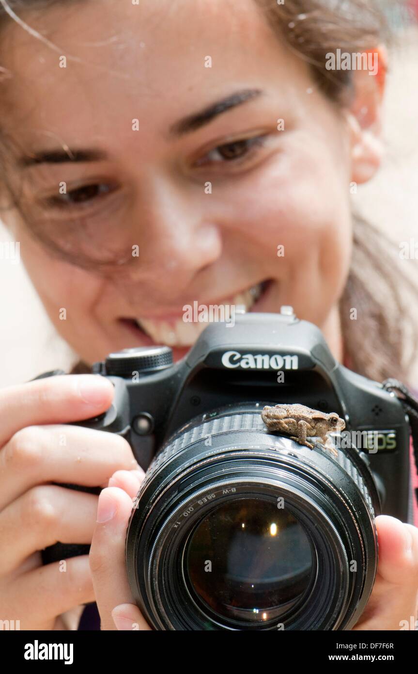 Young photographer woman using Canon brand camera funnily