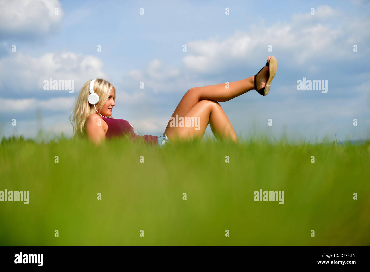 Young blonde woman lying in the grass and listening to music Stock ...