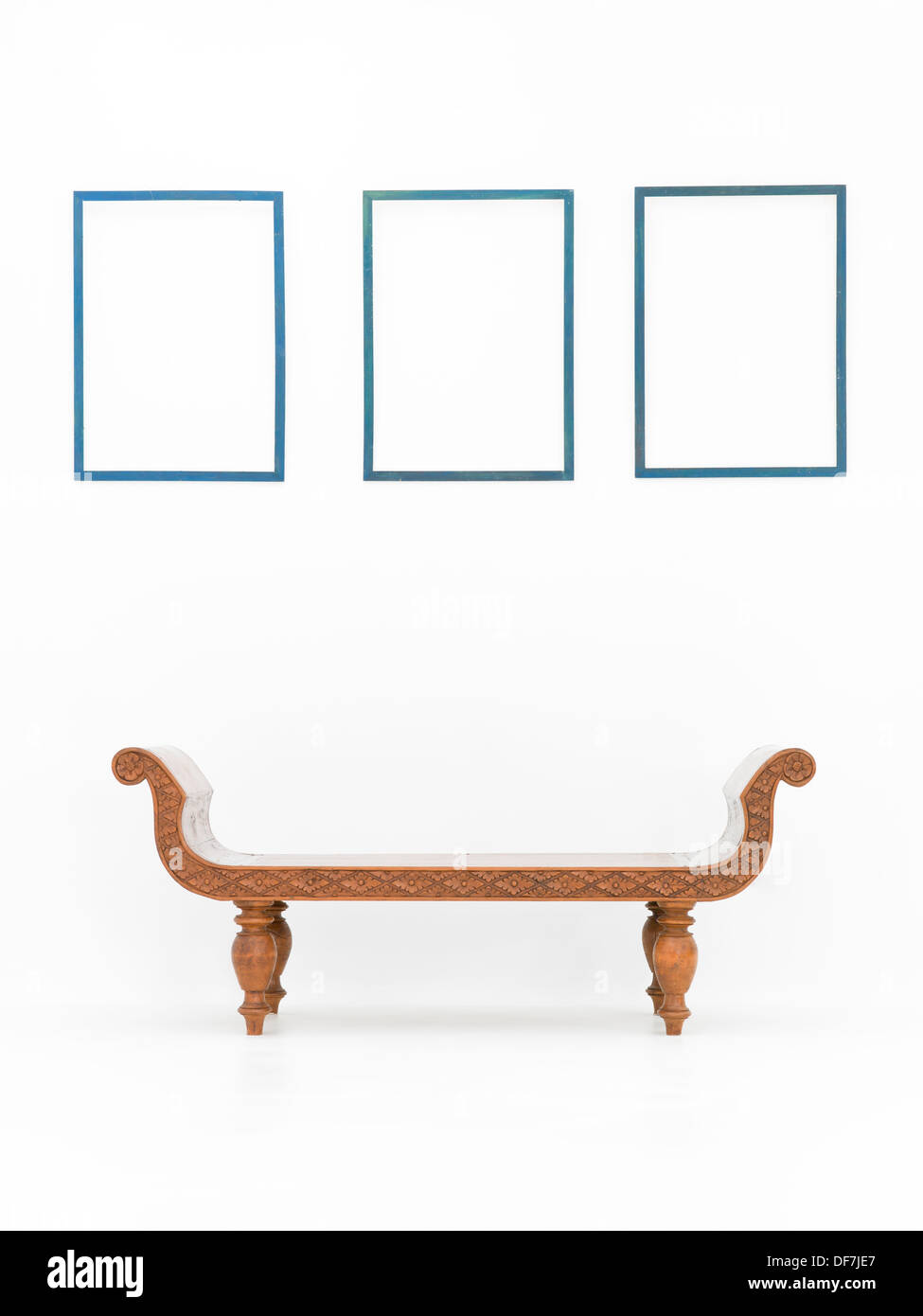 brown wooden bench in an empty white room with blue frames on walls Stock Photo